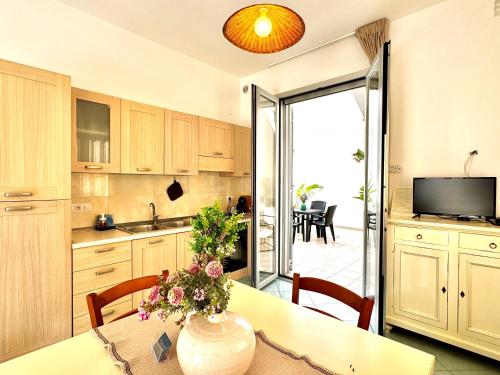 a kitchen with a table with a vase of flowers on it at Casa Appia, fronte mare con giardino - Marea Stays Collection in Nardò