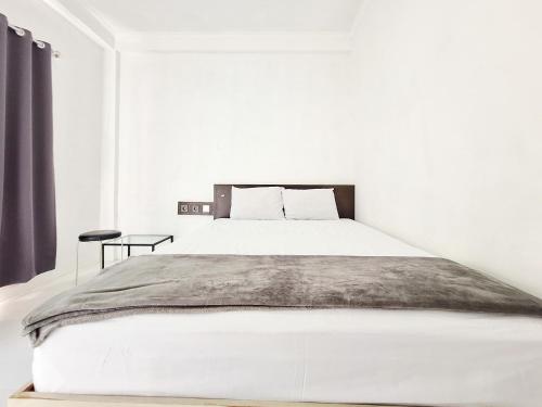 a white bedroom with a large bed and a table at Niti Stay Syariah near Stasiun Wates RedPartner in Wates