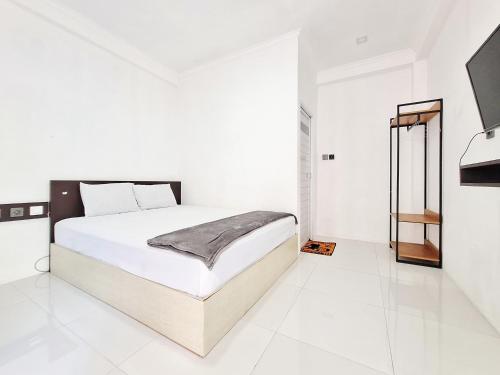 a white bedroom with a bed and a mirror at Niti Stay Syariah near Stasiun Wates RedPartner in Wates