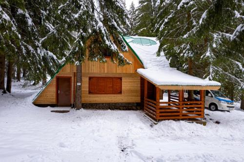 a cabin with a snow covered roof in the woods at Chata Jakobina in Pribylina