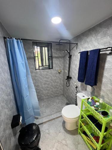 a bathroom with a toilet and a blue shower curtain at Upendo Moja House in Nkoanrua