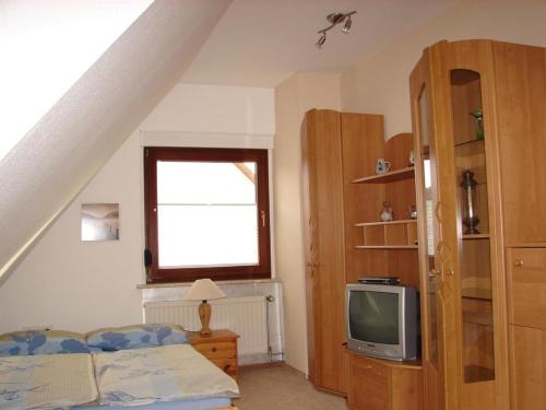 a bedroom with a bed and a tv at Gästehaus unter den Weinbergen in Laucha