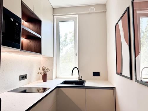 a kitchen with white counters and a sink and a window at Premium Art Deco Loft in Iaşi