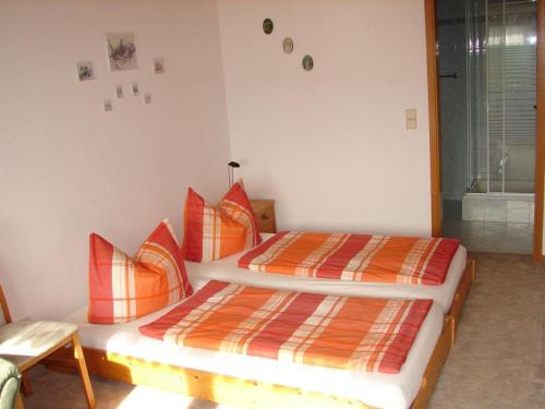 a bedroom with a bed with orange and orange pillows at Gästehaus unter den Weinbergen in Laucha