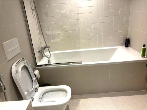 a bathroom with a toilet and a bath tub at Palm View Marina Vista 1BR Beachfront in Dubai