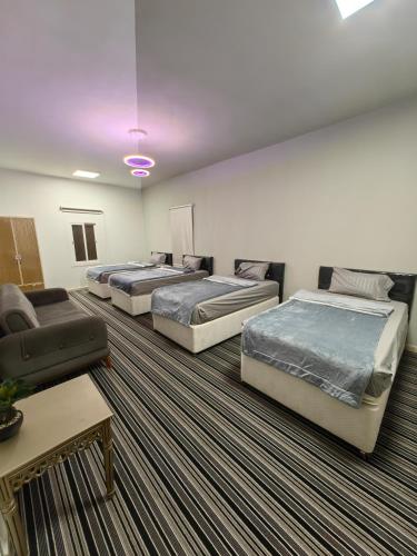 ein Zimmer mit drei Betten und einer Couch in der Unterkunft فيلا وشاليه نسيم لافا in Rayyis