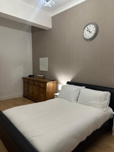 エディンバラにあるDouble room with garden In The Heart of Edinburghの壁に時計が付いたベッドのある寝室