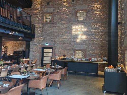 a restaurant with tables and chairs and a brick wall at Hotel Liberty Offenburg in Offenburg