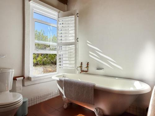a white bathroom with a tub and a window at Cedarpeak Mountain cottages in Piketberg