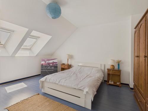a white bedroom with a bed and a wooden cabinet at Maison pour 4 avec jardin sur Guerande in La Baule