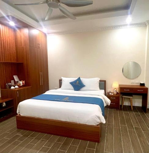 a bedroom with a large bed with blue and white pillows at Royal Louis Hotel in Dai Mo