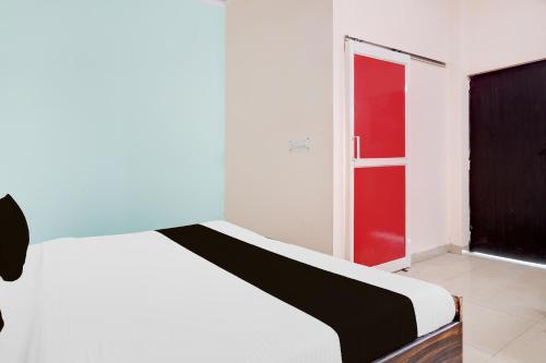 a bedroom with a white bed and a red door at SPOT ON Hotel Dezire Dhankot Chowk in Gurgaon