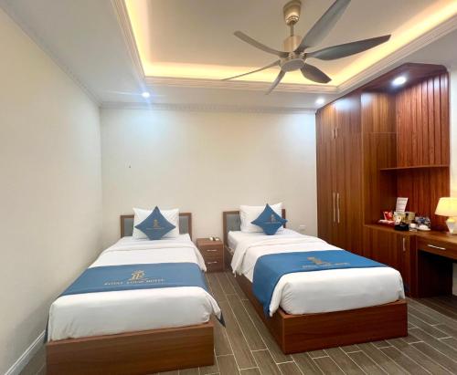 a bedroom with two beds and a ceiling fan at Royal Louis Hotel in Dai Mo