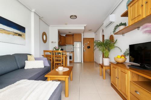 a living room with a blue couch and a kitchen at Apartment Costa Blanca Cabo Roig in Playas de Orihuela