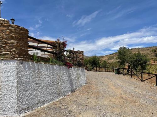 a stone wall with flowers on it next to a fence at Casa Crisantemo with sea view and pool in Adra in Las Hoyas del Barranco