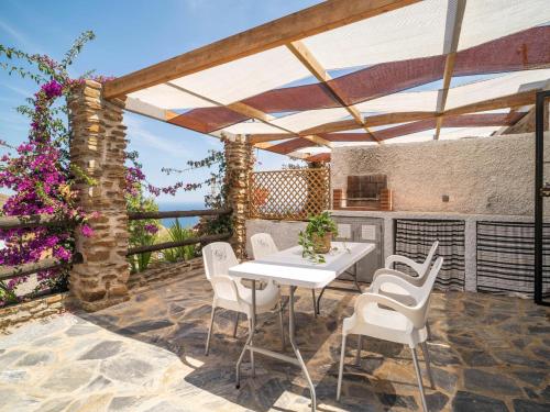 a patio with a white table and white chairs at Casa Crisantemo with sea view and pool in Adra in Las Hoyas del Barranco
