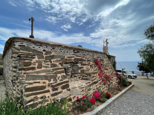 a stone wall with flowers and a cross on top at Casa Crisantemo with sea view and pool in Adra in Las Hoyas del Barranco