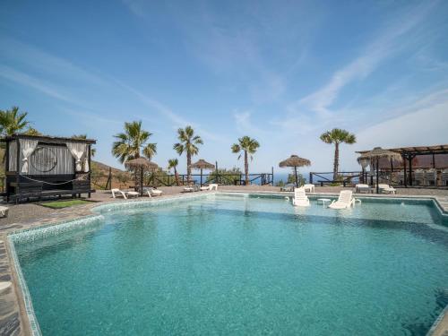 a large swimming pool with chairs and umbrellas at Casa Crisantemo with sea view and pool in Adra in Las Hoyas del Barranco