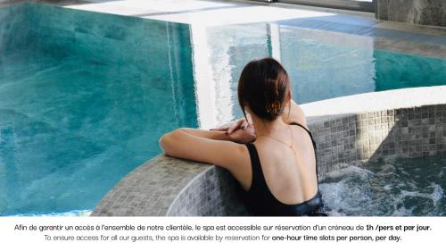 a woman sitting next to a swimming pool at Le Saint Gervais Hotel & Spa Handwritten Collection in Saint-Gervais-les-Bains
