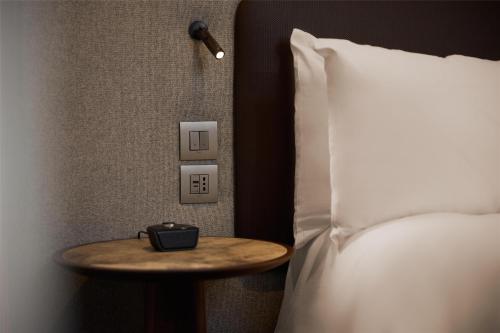 a nightstand next to a bed with a clock on it at Hilton Milan in Milan