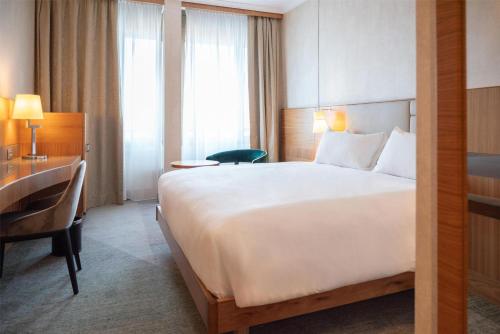a hotel room with a large bed and a desk at Hilton Milan in Milan