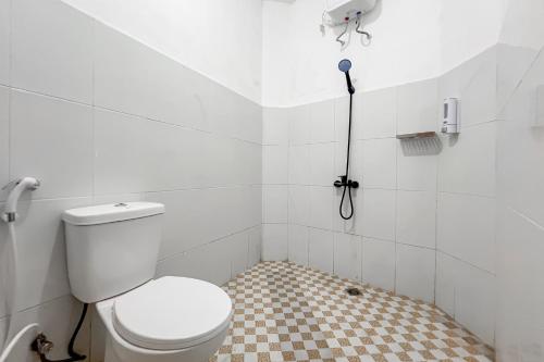 a bathroom with a white toilet and a checkered floor at RedDoorz at Dimens House Sragen in Sragen
