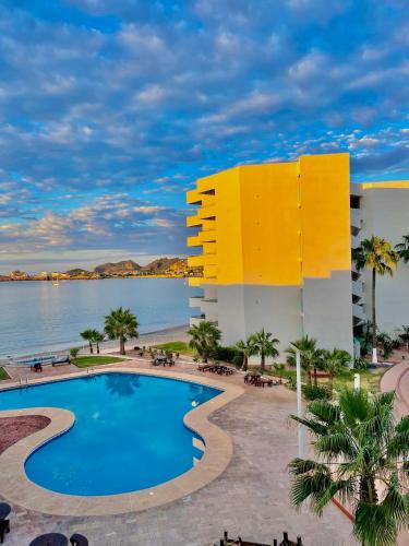 a resort with a swimming pool and a yellow building at Suite Posada frente al mar, Si San Carlos 312 in San Carlos