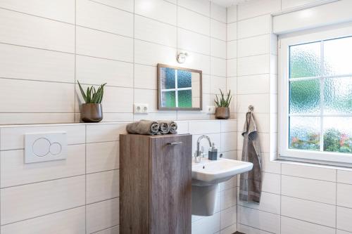 a white bathroom with a sink and a mirror at Ferienhaus Schenum in Jever