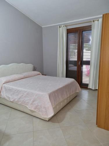 Una habitación blanca con una cama y una ventana en Casa Alessia, en SantʼAnna Arresi
