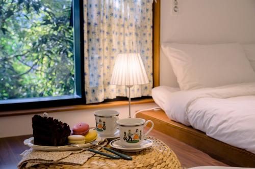 a room with a bed and a table with cups and desserts at 월영사계 in Seogwipo
