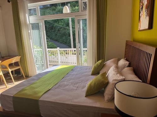 キャンディにあるThe Green Lodge Kandyの大きなベッドと大きな窓のある寝室