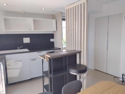 une cuisine avec des placards blancs, une table et un tabouret dans l'établissement Apartmán pod Kolibou, à Bratislava