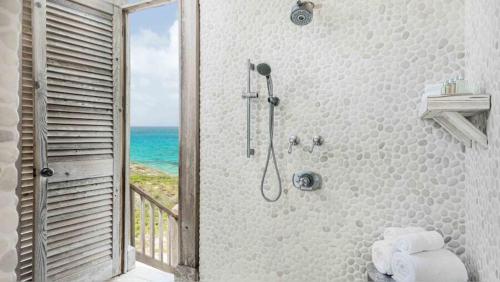 a bathroom with a shower with a view of the ocean at Ambergris Cay - Private Island All-Inclusive in Big Ambergris Cay