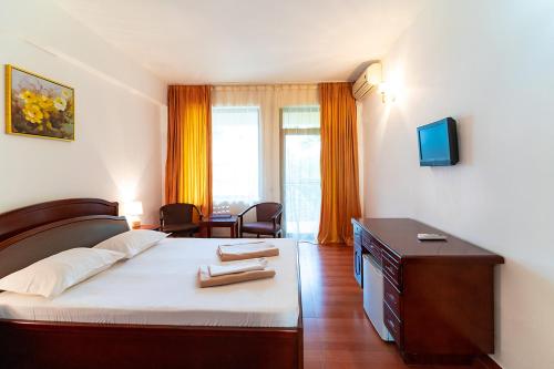 ein Schlafzimmer mit einem Bett und einem Schreibtisch mit einem Fernseher in der Unterkunft Hotel Victoria in Costinești