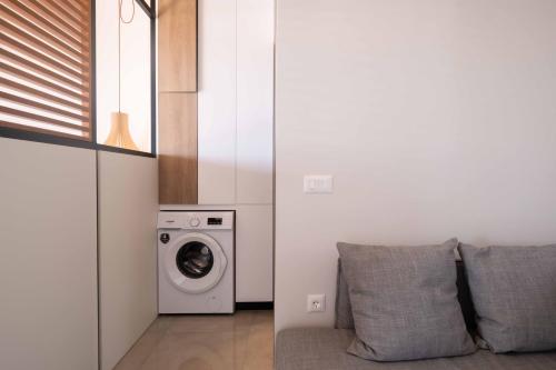a laundry room with a washing machine and a couch at See2sea Cozy Apartments in Kolymvari