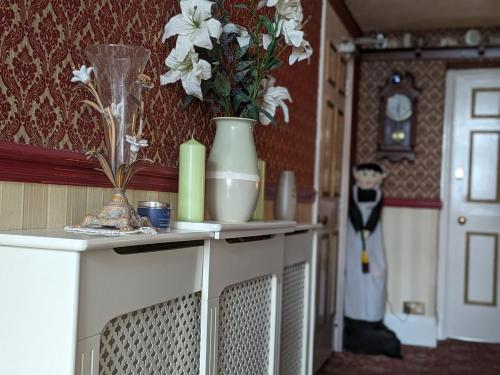 una mesa con jarrones y flores encima en Sunnycroft Private Hotel, en Llandudno