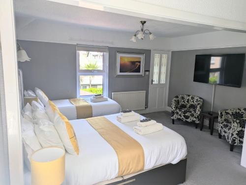 Una habitación de hotel con dos camas y un televisor. en Sunnycroft Private Hotel, en Llandudno