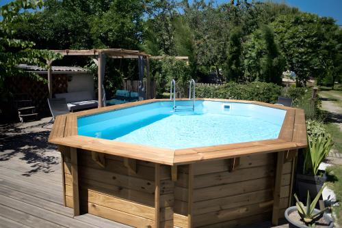 a hot tub in a deck with a swimming pool at Gite Fil Rouge in Saint-Pierre-dʼAurillac