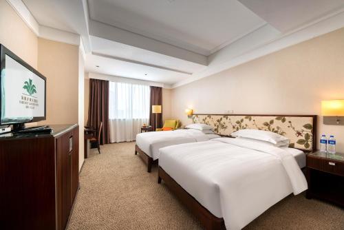 a hotel room with two beds and a flat screen tv at Harriway Garden Hotel Houjie in Dongguan
