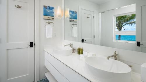a white bathroom with two sinks and a mirror at Ambergris Cay - Private Island All-Inclusive in Big Ambergris Cay