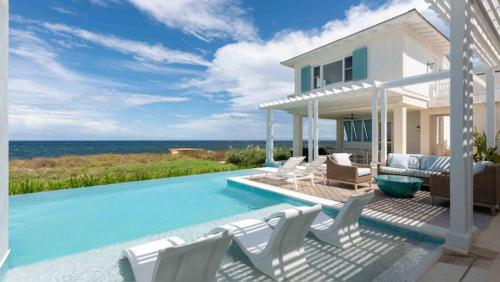 a house with a swimming pool next to the ocean at Ambergris Cay - Private Island All-Inclusive in Big Ambergris Cay