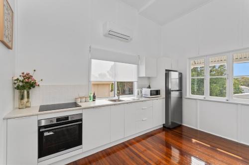 a kitchen with white cabinets and a refrigerator at Townsville Suites in Townsville