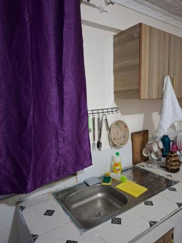 a kitchen with a purple curtain over a sink at Humility -Jasmine in Naro Moru