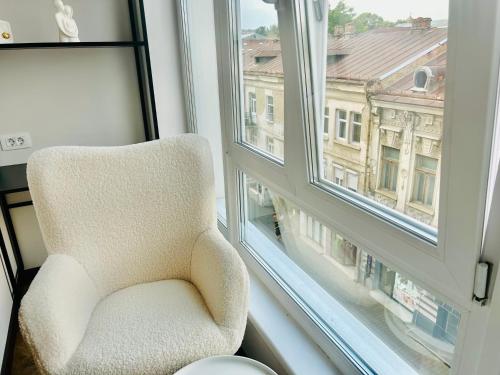 a white chair sitting in front of a window at Old Town Luxe Loft in Iaşi