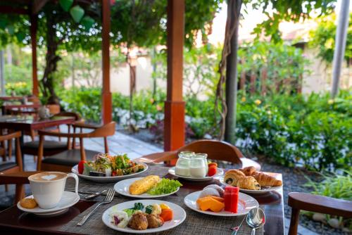 a table with plates of food and cups of coffee at Silk Sense Hoi An River Resort - Green Luxury Escape in Hoi An