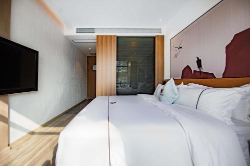 a hotel room with a large white bed and a flat screen tv at Leader Art Hotel（Shenzhen University Science and Technology Park Store)） in Shenzhen