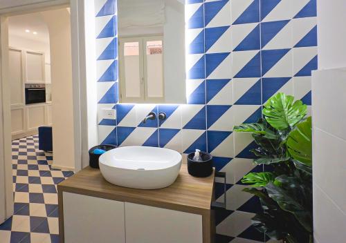 a bathroom with a white sink and blue and white tiles at Marina Palace Apartments & Terrace in Lipari