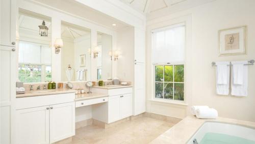 a white bathroom with two sinks and a tub at Ambergris Cay - Private Island All-Inclusive in Big Ambergris Cay