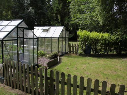two greenhouses in a garden behind a fence at Charming Chalet with Swimming Pool in Quend in Quend