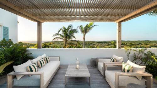 a patio with a couch and tables and palm trees at Ambergris Cay - Private Island All-Inclusive in Big Ambergris Cay